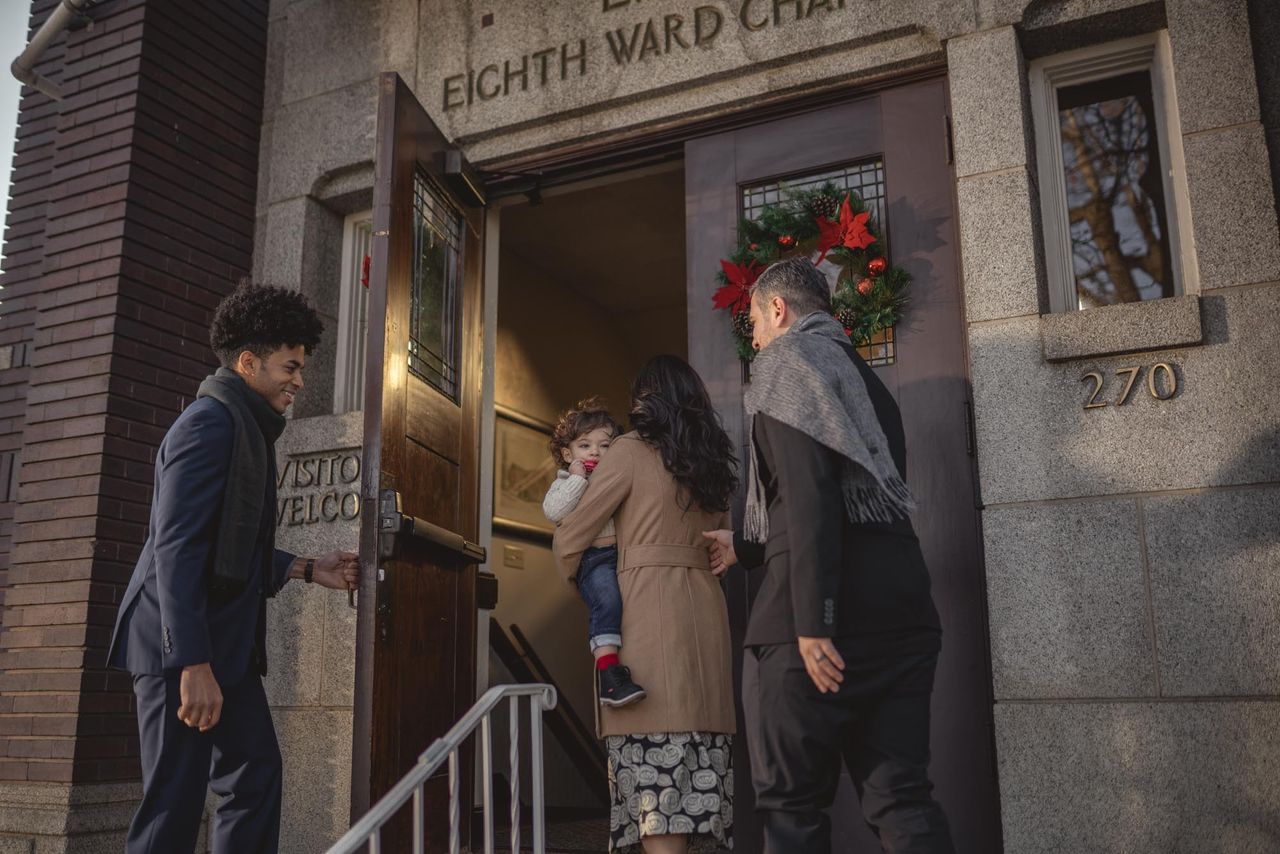Um jovem abre a porta da Igreja para uma família