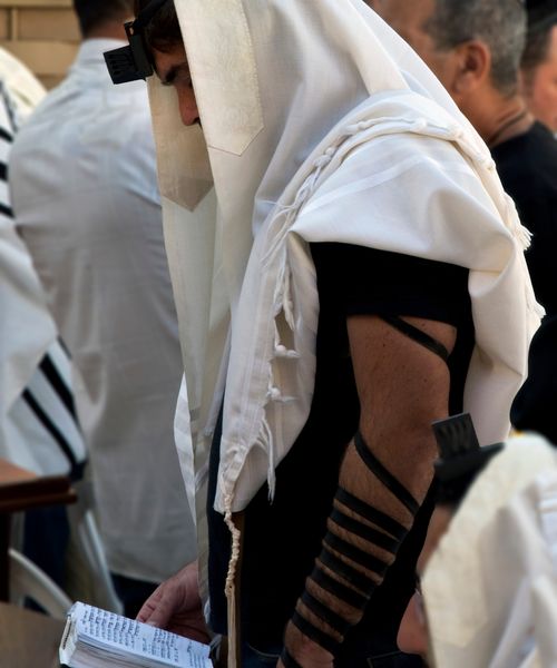 un hombre con filacterias modernas alrededor del antebrazo y la frente