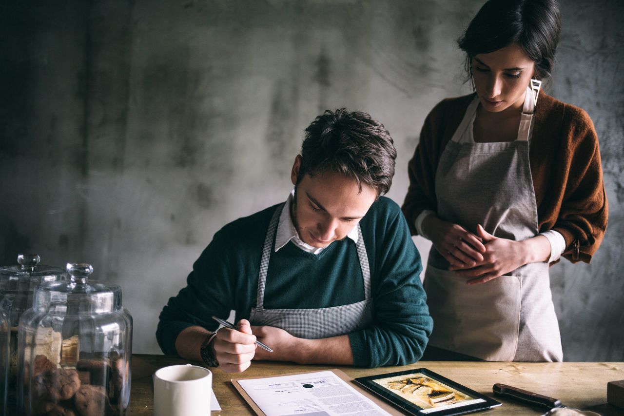 Una pareja sentada a la mesa revisando una receta de cocina
