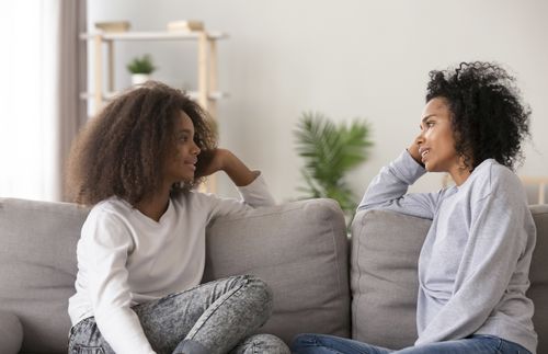 mom listening to teen daughter as they sit on couch together