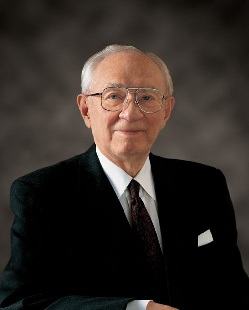 A portrait of President Gordon B. Hinckley smiling in a black suit, white shirt, and glasses.