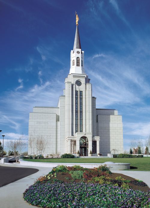 A front view of sidewalks and vegetation leading to the Boston Massachusetts Temple on a sunny day.