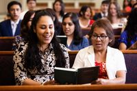 Duas mulheres compartilhando um hinário durante as reuniões da igreja