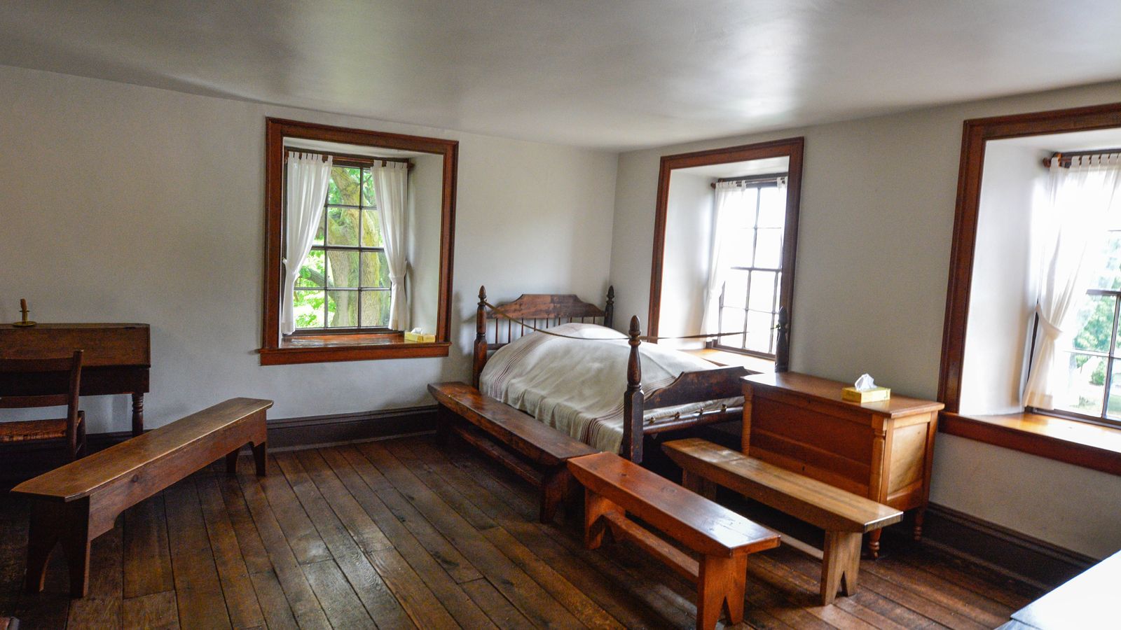 A bed sits in a room with three large windows where Joseph and Hyrum Smith were martyred.