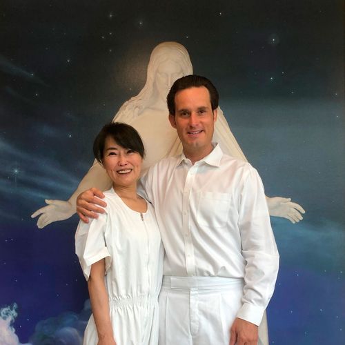 une femme et un homme en vêtements de baptême devant une image représentant le Sauveur