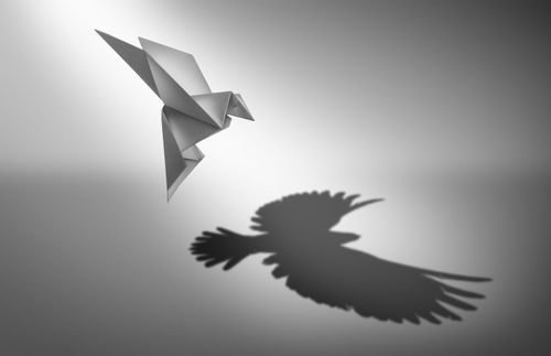 Ein Origami-Vogel mit dem Schatten eines echten Vogels