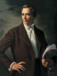 Half-length frontal portrait of the Prophet Joseph Smith, Jr. Joseph's head is turned to the side in a three-quarter view, right hand on hip and his left hand holds sheets of papers. He is depicted wearing a dark brown suit and a white shirt and tie.