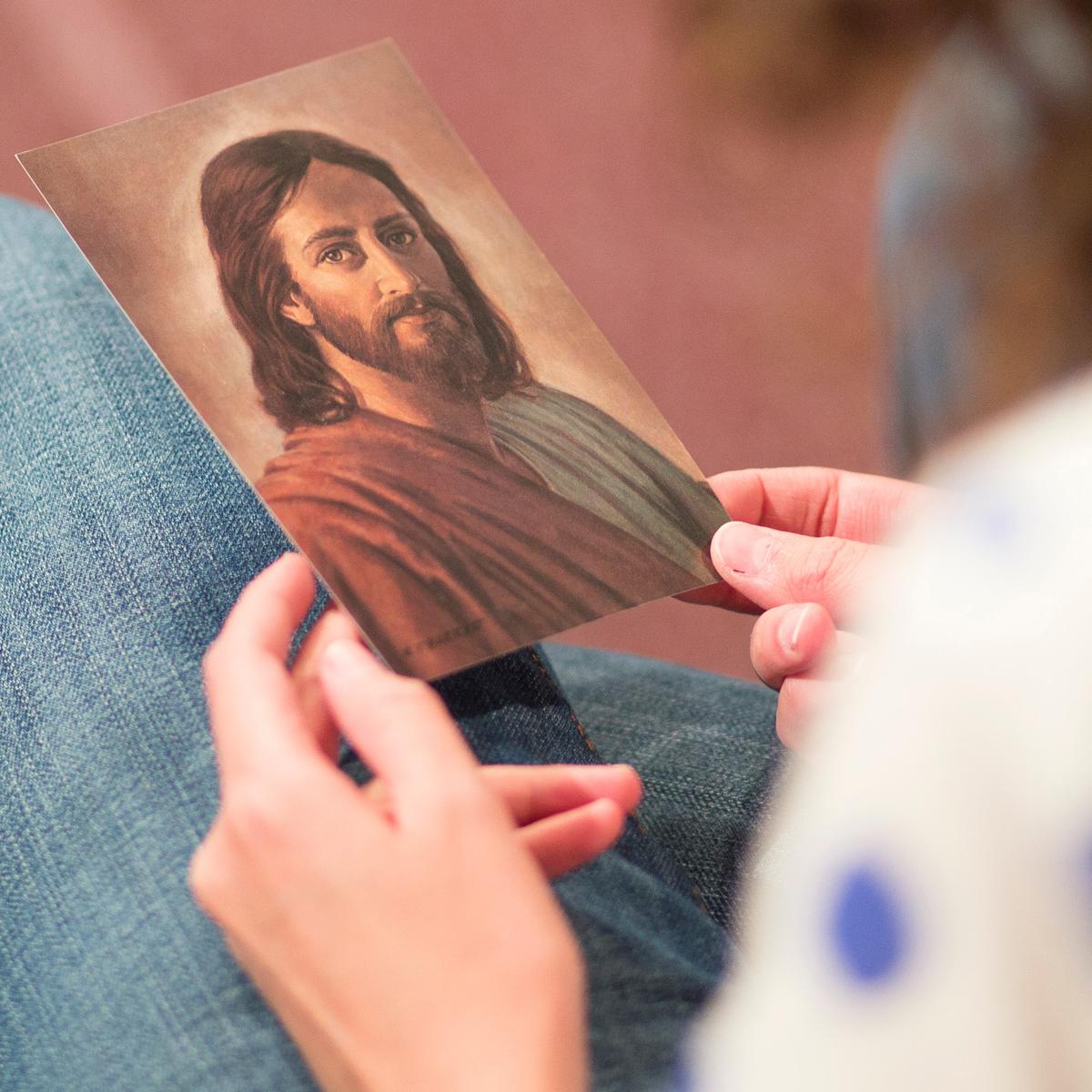 young woman looking at picture of Christ